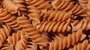 Uncooked Whole Grain Fusilli Pasta. A Culinary Canvas of Whole Wheat Spirals, Textured Background - Top View, Rotating. Turning Whole Grain Twisted Dry Pasta. Whole Wheat Raw Macaroni - Rotation video