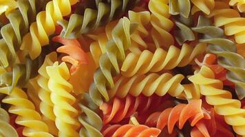 Uncooked Vibrant Colored Fusilli Pasta. A Mesmerizing Culinary Canvas of Multicolored Spirals, Textured Background - Rotating. Turning Colored Dry Pasta. Raw Macaroni - Rotating video