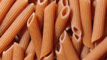 Uncooked Whole Grain Penne Rigate Pasta. A Culinary Canvas of Whole Wheat Macaroni, Textured Background - Top View, Rotating. Turning Whole Grain Dry Pasta. Whole Wheat Raw Macaroni - Side Rotation video