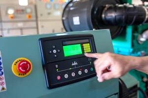 A person is pointing at a control panel in a factory photo