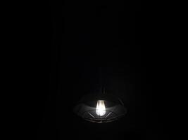 A light bulb is hanging from a black ceiling photo