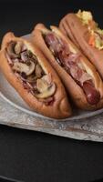 Hotdog with grilled sausage with bacon and mushrooms in a bun with salt, spices and herbs video