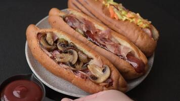 Hotdog with grilled sausage with bacon and mushrooms in a bun with salt, spices and herbs video