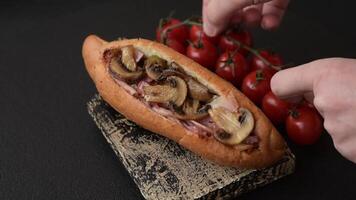Hotdog with grilled sausage with bacon and mushrooms in a bun with salt, spices and herbs video