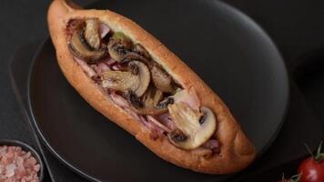 Hotdog with grilled sausage with bacon and mushrooms in a bun with salt, spices and herbs video
