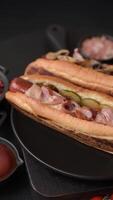 Hotdog with grilled sausage with bacon and mushrooms in a bun with salt, spices and herbs video