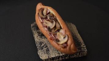 Hotdog with grilled sausage with bacon and mushrooms in a bun with salt, spices and herbs video