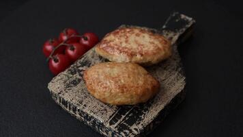 Delicious fresh fried minced fish cutlets with spices and herbs on a dark concrete background video