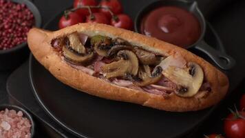 Hotdog with grilled sausage with bacon and mushrooms in a bun with salt, spices and herbs video