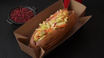 Hotdog with grilled sausage with cabbage, carrots and onions in a bun with salt, spices and herbs video