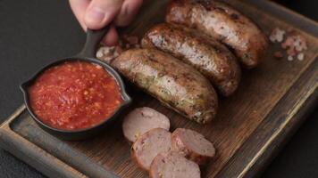 Juicy sausages with salt, spices and herbs grilled on a dark concrete background video