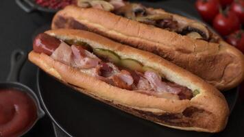 Hotdog with grilled sausage with bacon and mushrooms in a bun with salt, spices and herbs video