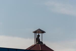 A statue of a buddha on top of a building photo