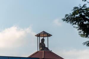 A statue of a buddha on top of a building photo