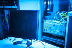 A computer monitor sitting on a desk in a server room photo