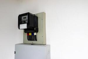 A meter is mounted on a wall with wires attached photo