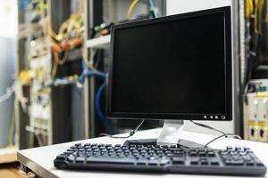 A computer monitor and keyboard on a desk in a server room photo