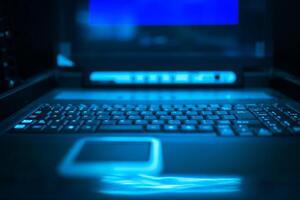 A computer keyboard is lit up in blue photo