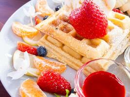 A plate of waffles with fruit and a bowl of fruit photo