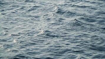 Sea wave close up, low angle view. Abstract background of flow of sea water in sunlight. Blue ocean surface video