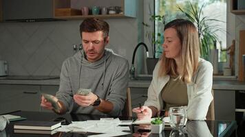 Worried couple calculating domestic bills and counting remaining money, Worried man and woman sitting at kitchen table and planning family budget. Concept of rising costs in households video