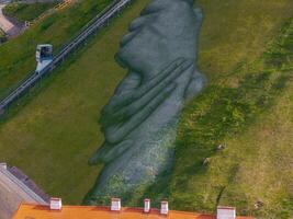 Aerial View of Clasped Hands Artwork on Grassy Hillside in Vilnius photo