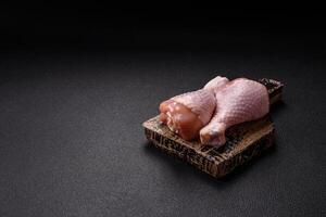 Raw chicken legs with salt, spices and herbs photo