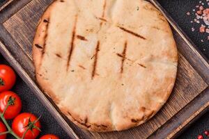 Round flatbread or pita with cheese, herbs, salt and spices photo