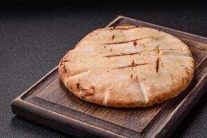 Round flatbread or pita with cheese, herbs, salt and spices photo