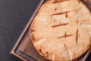 Round flatbread or pita with cheese, herbs, salt and spices photo