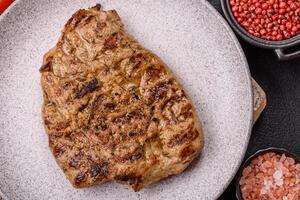 Grilled beef or pork steak with salt, spices and herbs photo