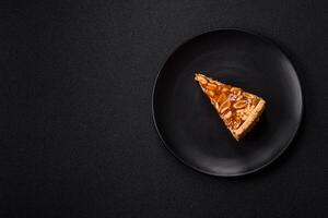 Delicious fresh cheesecake caramel peanut cake with cream and nuts on a ceramic plate on a dark concrete background photo