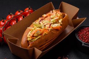Hotdog with grilled sausage with cabbage, carrots and onions photo