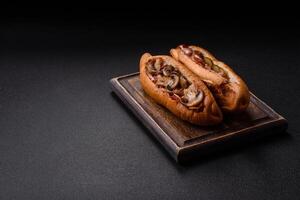 Hotdog with grilled sausage with bacon and mushrooms photo