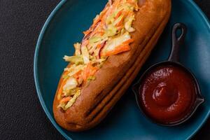 Hotdog with grilled sausage with cabbage, carrots and onions photo