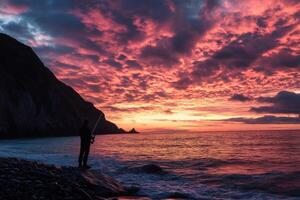 Fisherman enjoying stunning sunset over ocean and mountains photo