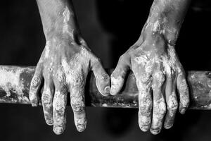 Gymnast gripping uneven bars with chalked hands in black and white photo