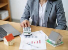 a woman sitting at a desk with a calculator and a laptop computer on it photo