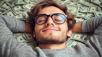 Relaxed young man lying on a pile of money with closed eyes and smiling photo