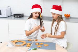 Two girls sisters are playing around in the kitchen after making Christmas cookies, they draw with flour on the table and on their faces. Christmas, New Year concept photo