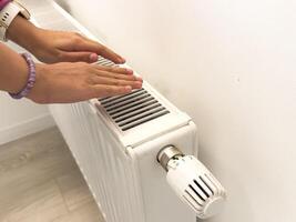 hand adjusting radiator temperature using thermostat. Home with central heating. photo