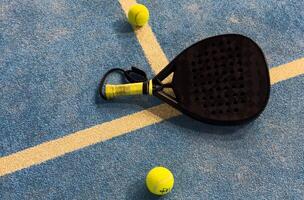 padel racket and yellow balls placed on court near net photo