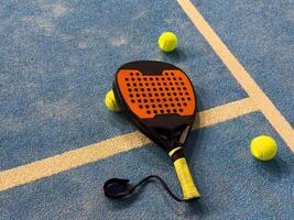 padel racket and yellow balls placed on court near net photo