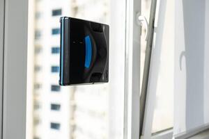 Robot window cleaner work on dirty window. Cleaning the house with smart devices. Automatic vacuum robots for cleaning windows, an assistant for the home. photo