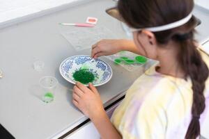 child learning research and doing a chemical experiment while making analyzing and mixing liquid in test glasses. Playful little girl in protective wear having fun playing with chemistry lab game photo