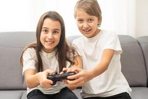 Two little girlfriends playing game with joysticks. Excited and focused european children. Childhood concept. Entertainment and leisure. Idea of friendship. Grey background in studio. Copy space photo