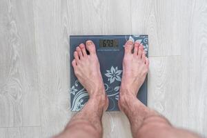 Man standing on weight scale photo