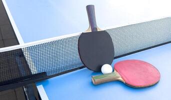 wooden rackets for playing table tennis and a net on a blue background, top view photo