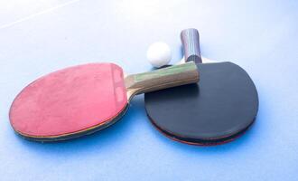 wooden rackets for playing table tennis and a net on a blue background, top view photo