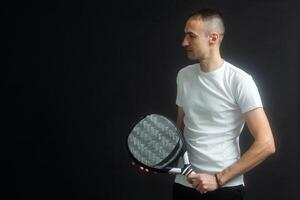 Portrait of man playing paddle tennis in position to hit a backhand ball black isolated background. Front view. photo